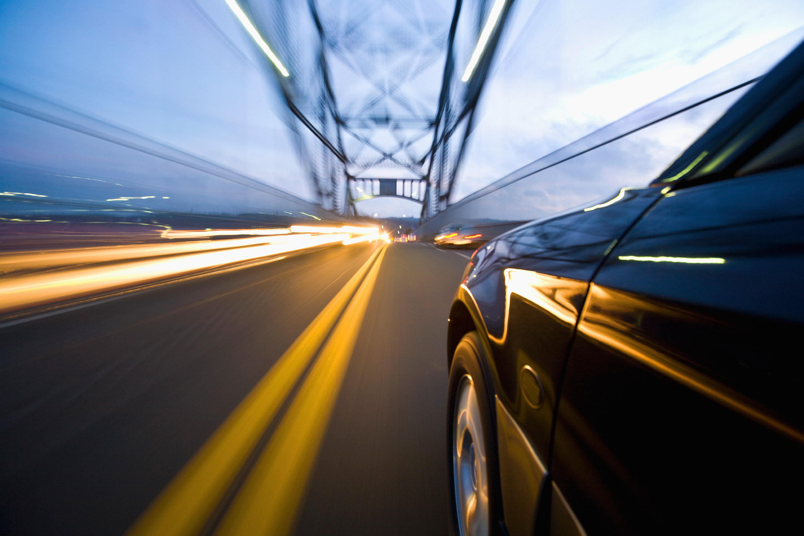 Auto de lujo circulando a alta velocidad sobre un puente de noche, dejando estelas de luz, imagen conceptual de agilidad y velocidad operativa con SAP Business One